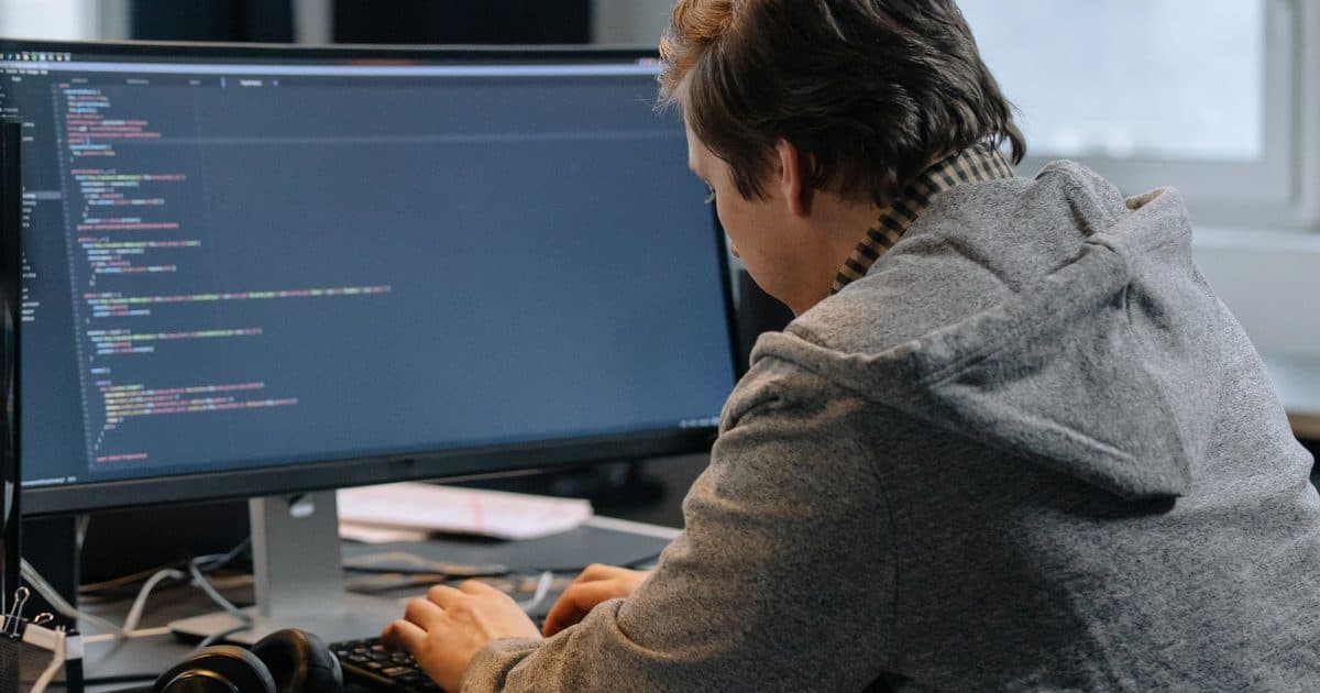 Software developer reviewing their LinkedIn profile on a monitor with code in the background