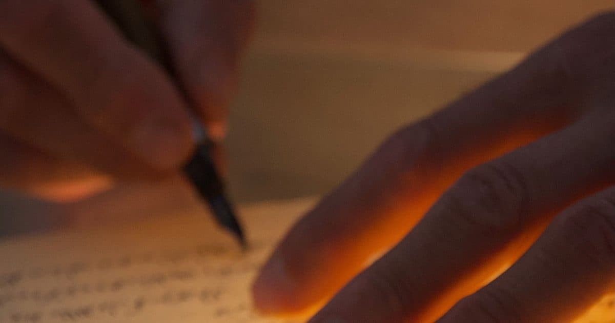 Person writing content for their LinkedIn profile in a notebook